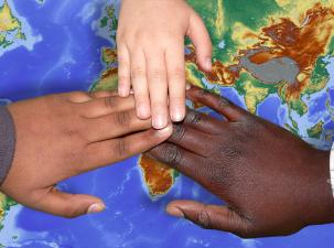 Drei Hände, die sich berühren über einer Weltkarte