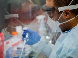 Ein Mensch in Schutzkleidung arbeitet in einem Labor