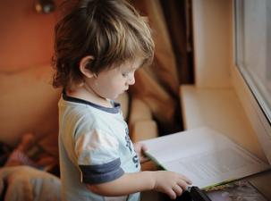 EIn Kind schaut auf eine Zeitung