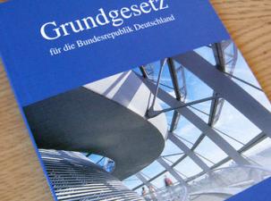 Das deutsche Grundgesetz in Buchform auf einem Tisch liegend
