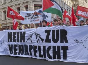 Eine Demo junger Menschen gegen die Wehrpflicht mit Bannern und Fahnen