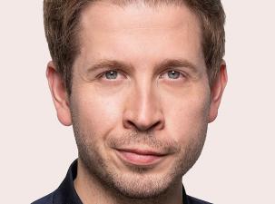 Foto von Kevin Kühnert: Ein Mann mit kurzen, blonden Haaren und einem neutralen Gesichtsausdruck. Er trägt ein dunkelblaues Oberteil. Hintergrund ist hell.