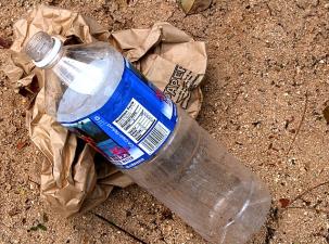 Eine Plastikflasche liegt am Strand