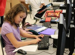 Ein Mädchen an einem PC in einer Schule