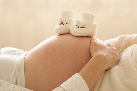 Schwangerschaftsbauch mit Babyschuhen