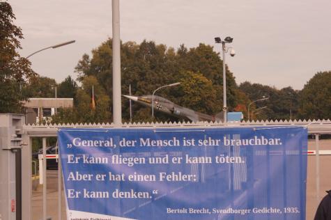 Ein Banner mit einer friedenspolitischen Aufschrift vor einer Jet-Statue