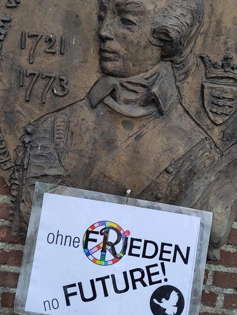 Eine Statue mit einem Plakat auf dem "Ohne Frieden no Future" steht