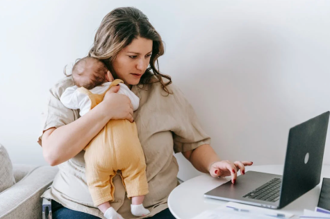 Mutter mit Baby im Arm am Laptop