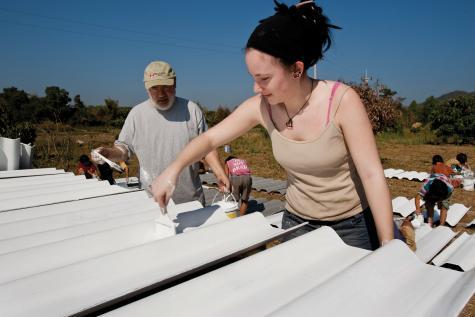 Mehrere Freiwillige bei Streicharbeiten auf einem Dach